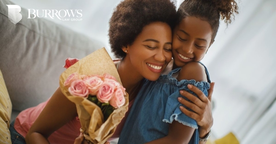 Mother receiving flowers from her daughter and hugging each other