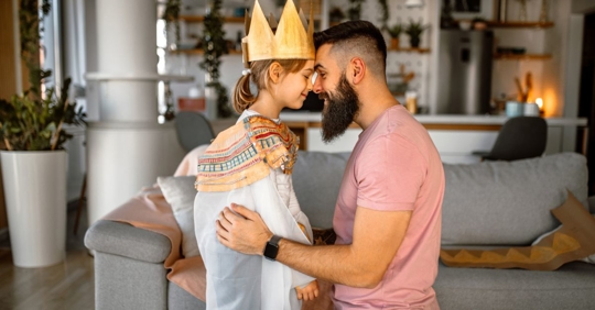 Cute daughter dressed in princess costume and her father standing face to face