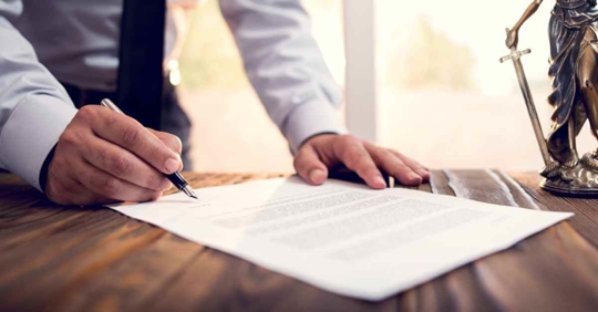 A person signing a document that is resting on a table