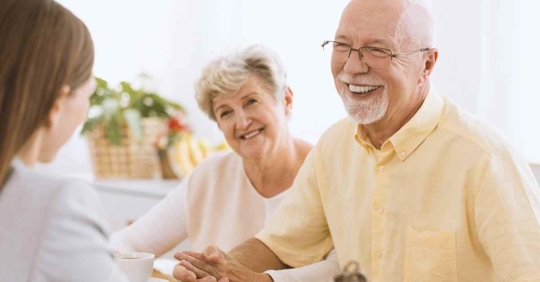 An older couple laughing and smiling while they review their estate plan with an attorney.