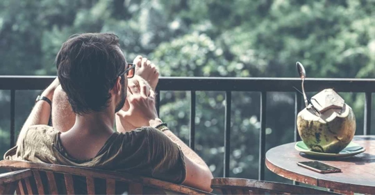 A man relaxing in a comfortable chair as he looks out over a balcony
