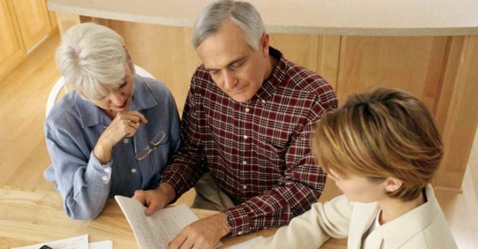 An older man and woman reviewing documents together with another woman.
