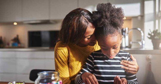 A mother hugging her daughter as she plays