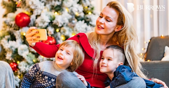mother taking a selfie with her children in front of a Christmas tree
