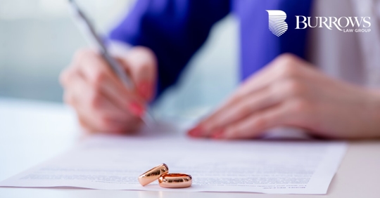 rings on a piece of paper with someone signing the paper in the background