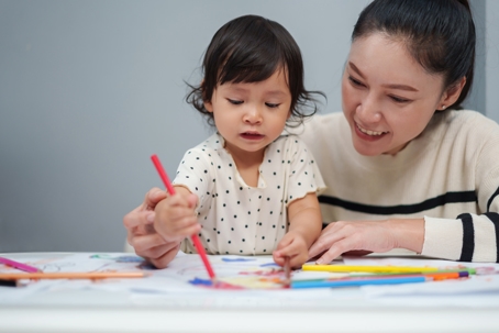 mother helping child color
